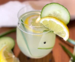 Erfrischender Gin-Tonic-Mocktail mit Zitronen- und Gurkenscheiben sowie Eiswürfeln in einem Glas, dekorativ serviert auf Holzuntergrund mit frischen Zutaten.