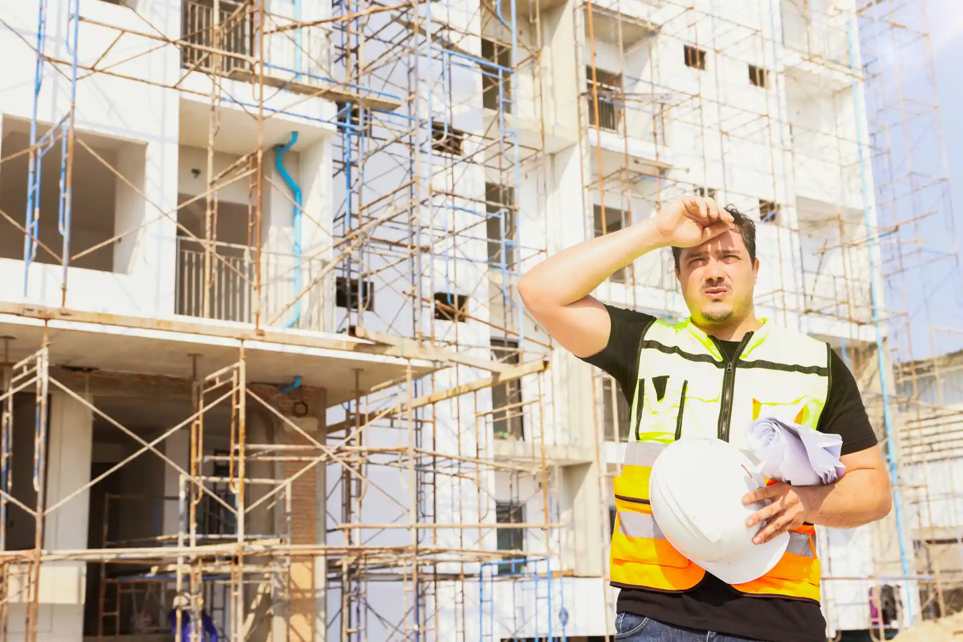 Bauarbeiter auf Baustelle wischt sich den Schweiß von der Stirn