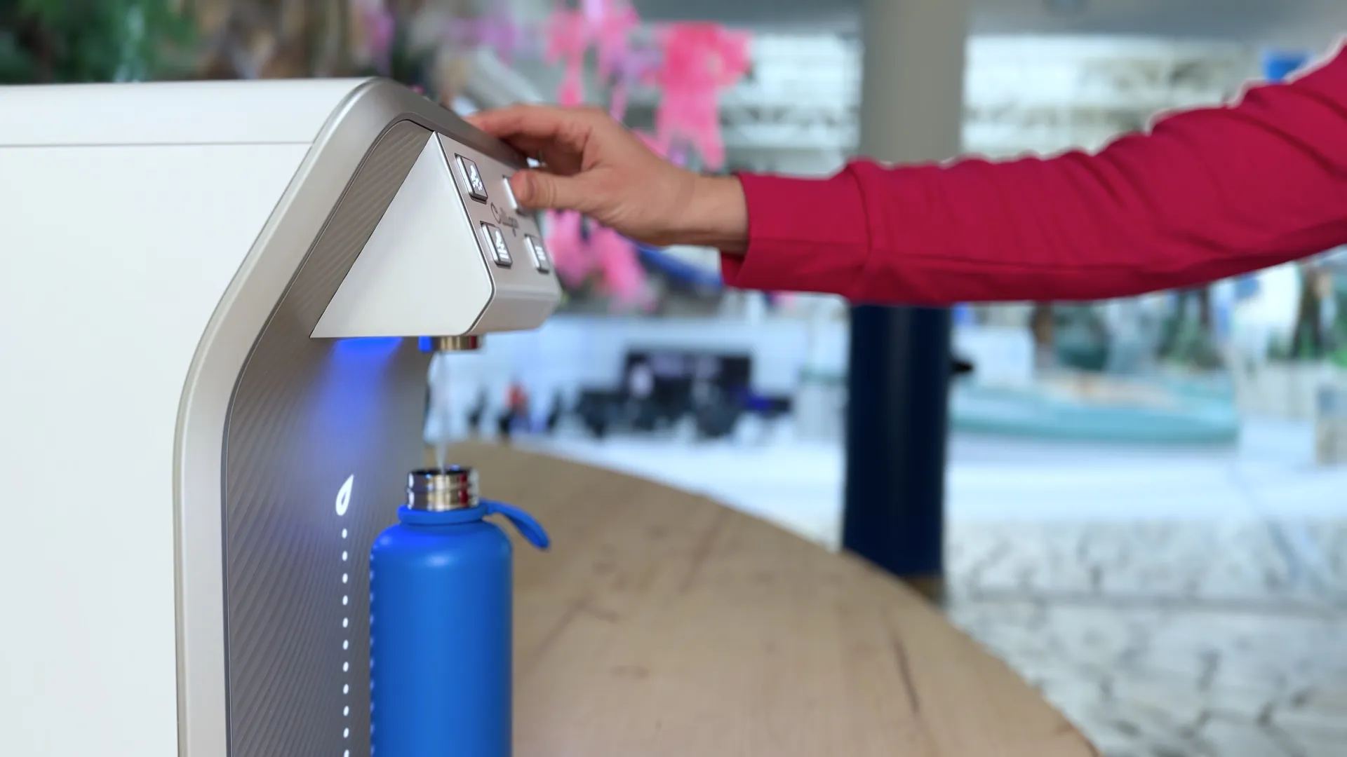 Mitglied von Row Inc füllt kaltes Wasser aus Culligan Wasserspender in Refill-Flasche